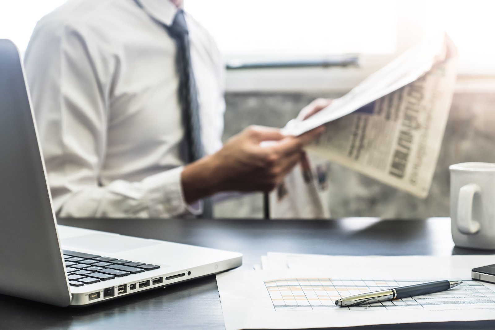 Businessman reading a newspaper on the desk. Selective focus